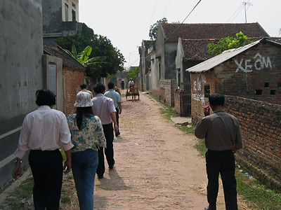 Photo 1 of 15 : The village streets of Thanh Gia in north Vietnam's rice-rich Red River region.  Families in this small hamlet of Bac Ninh Province have been living off the land and rice farming for centuries.  As a mule-drawn cart approaches, a painted sign promoting 'Xe Om' -- or motorbike taxi -- suggests a more modern road ahead. 